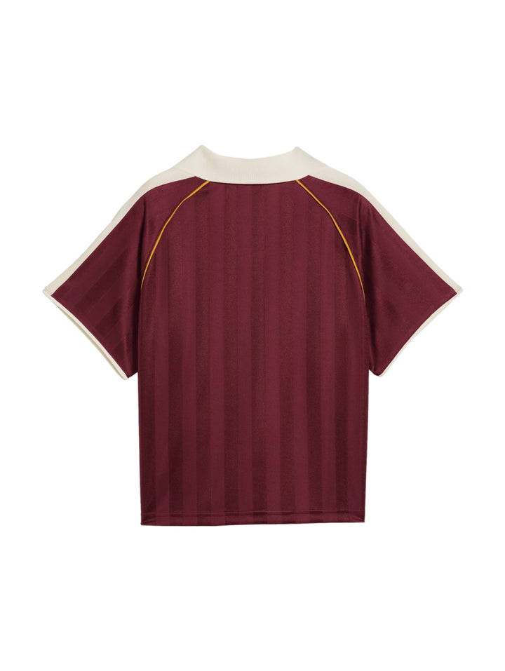Mujer vistiendo playera y shorts deportivos PUMA en color ruby shimmer heather con detalles en blanco y dorado.