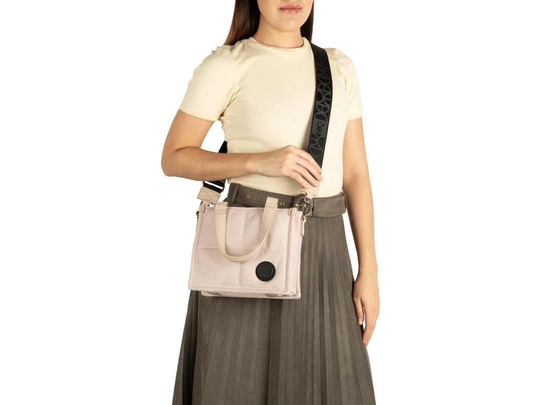 Bolso Cloe color beige con forma cuadrada, asas cortas y correa larga ajustable en color negro.