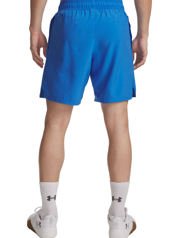 Hombre vistiendo shorts deportivos color azul de la marca Under Armour con logotipo lateral blanco.