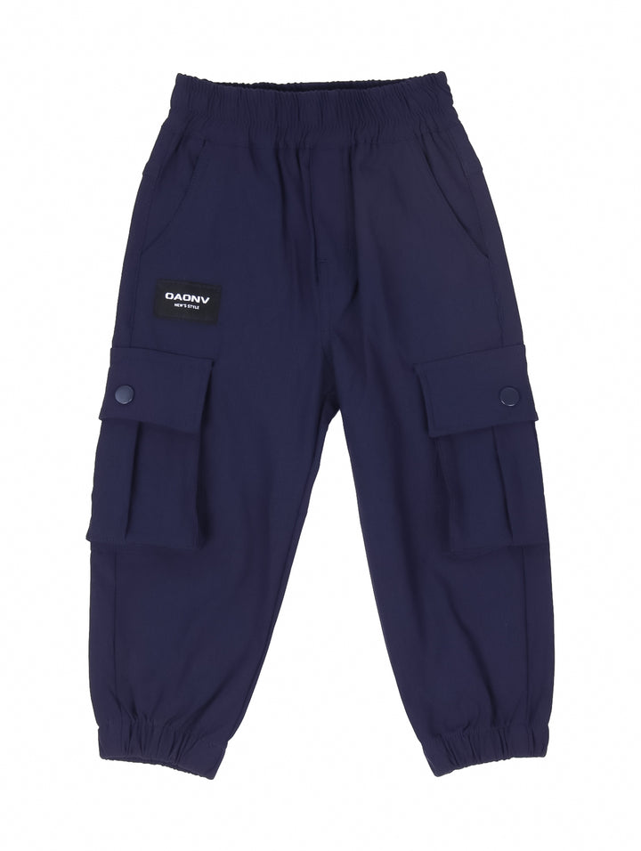 Niño vistiendo pantalón cargo color marino con bolsillos laterales y tenis blancos.