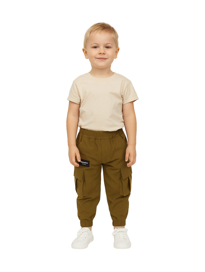 Niño vistiendo un pantalón cargo color verde oliva con bolsillos laterales y tenis blancos.