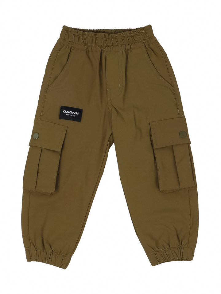 Niño vistiendo un pantalón cargo color verde oliva con bolsillos laterales y tenis blancos.
