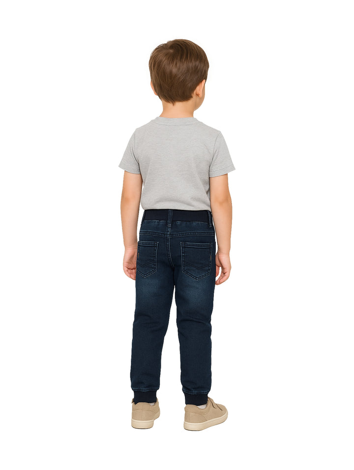 Niño modelando un pantalón de mezclilla azul oscuro con cintura elástica.