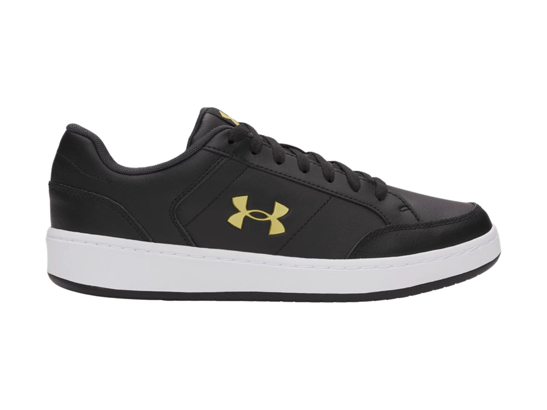 Tenis Under Armour color negro con suela blanca y logotipo dorado en el lateral.