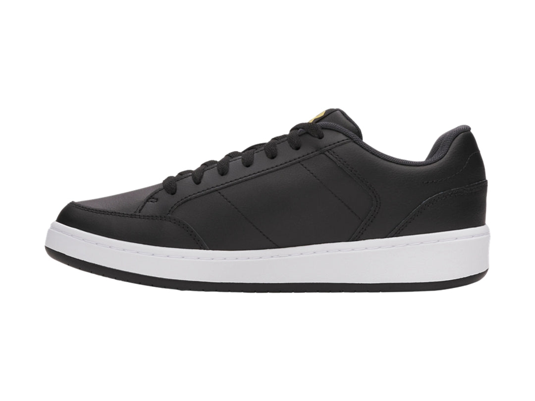 Tenis Under Armour color negro con suela blanca y logotipo dorado en el lateral.