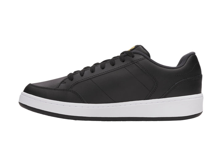 Tenis Under Armour color negro con suela blanca y logotipo dorado en el lateral.