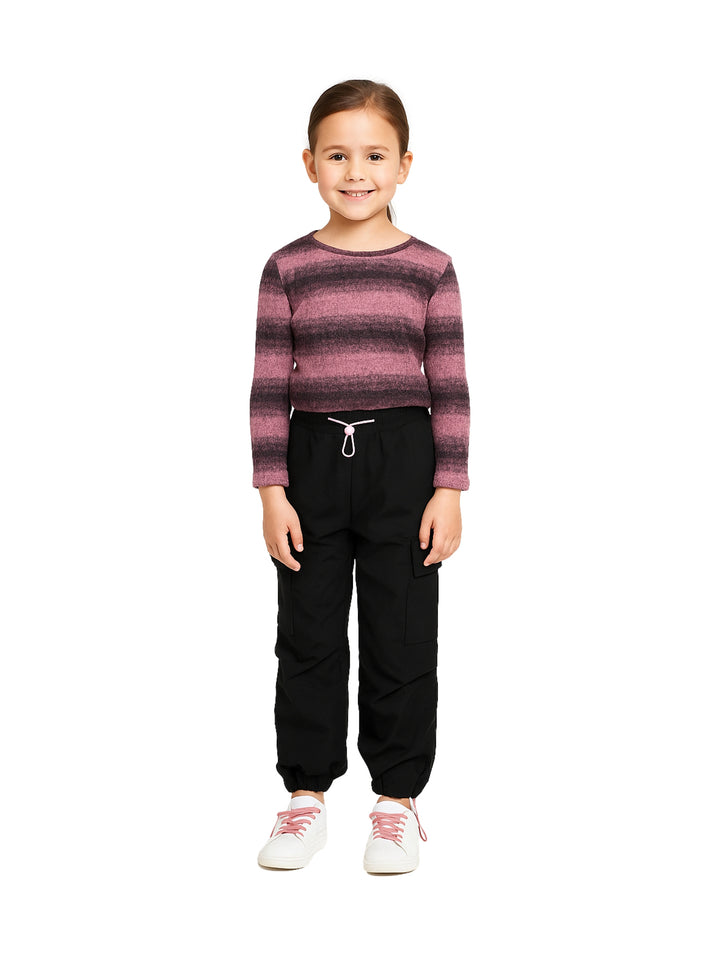 Niña vistiendo conjunto de camiseta rosa a rayas y pantalón cargo negro con tenis blancos.