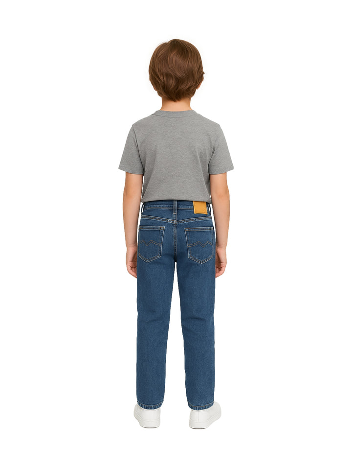 Niño vistiendo pantalones jeans azul doble stone de corte recto y camiseta gris.