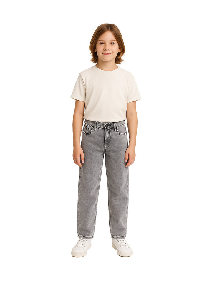 Niño vistiendo un pantalón vaquero color gris de corte recto y camiseta blanca.