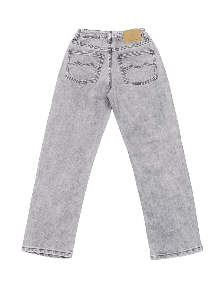Niño vistiendo un pantalón vaquero color gris de corte recto y camiseta blanca.