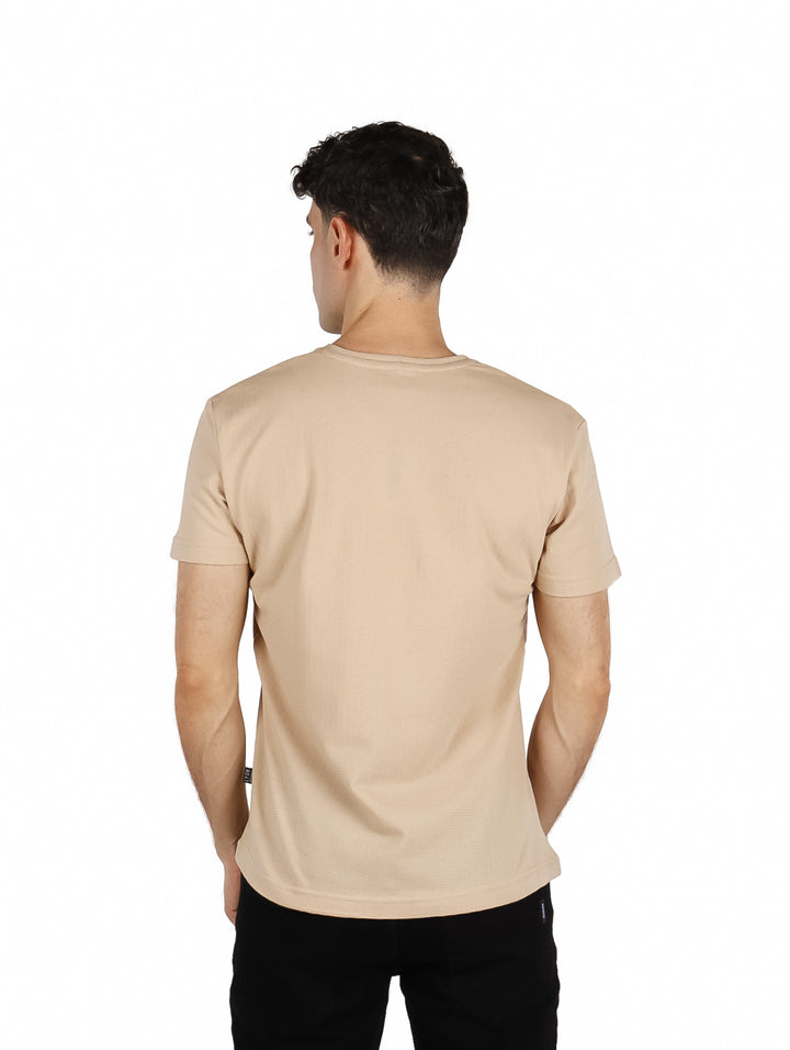 Hombre vistiendo una playera básica de color beige con cuello redondo y manga corta.