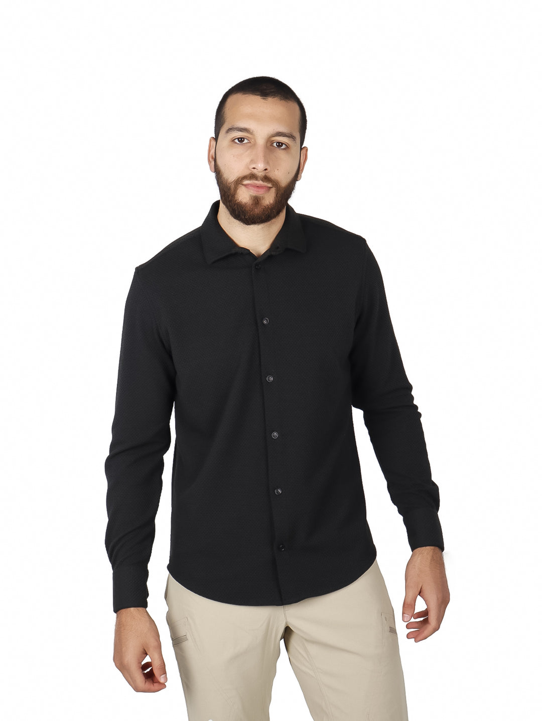Hombre vistiendo una camisa negra de manga larga con botones y pantalones beige.