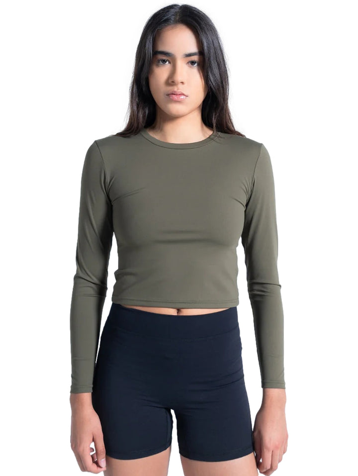 Mujer vistiendo playera deportiva manga larga color olivo de corte corto y shorts negros.