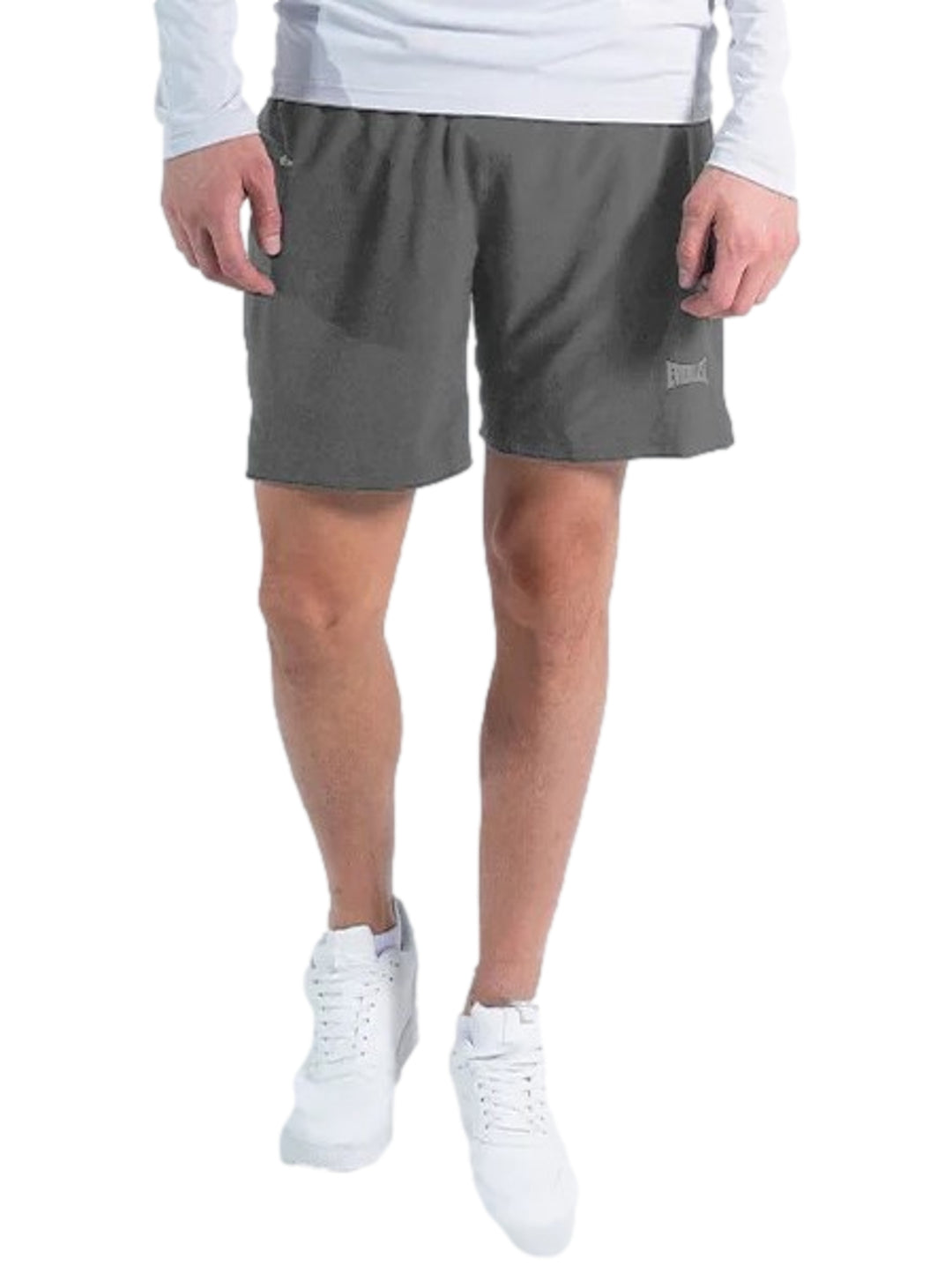 Hombre vistiendo shorts deportivos de color gris marca Everlast con calzado blanco.