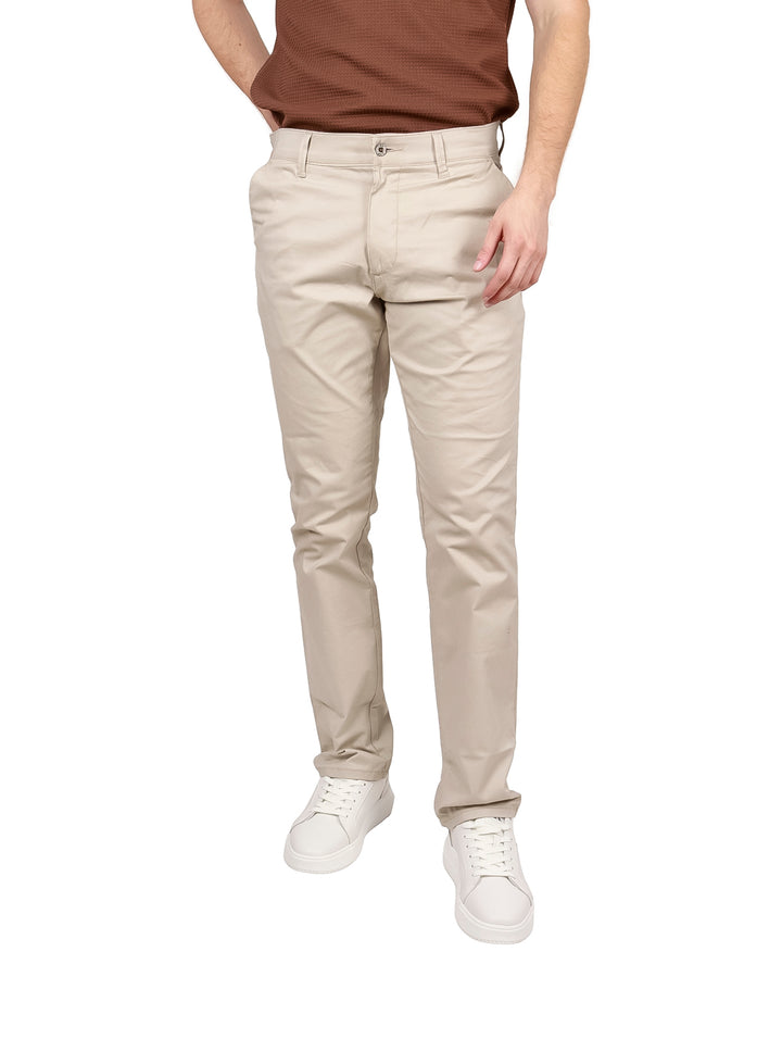 Hombre vistiendo pantalones LEE color beige de corte slim fit y tenis blancos.
