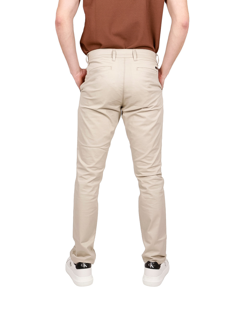 Hombre vistiendo pantalones LEE color beige de corte slim fit y tenis blancos.