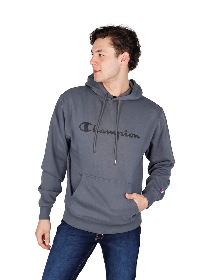 Hombre vistiendo una sudadera con capucha color gris oscuro de la marca Champion con logotipo en el pecho.