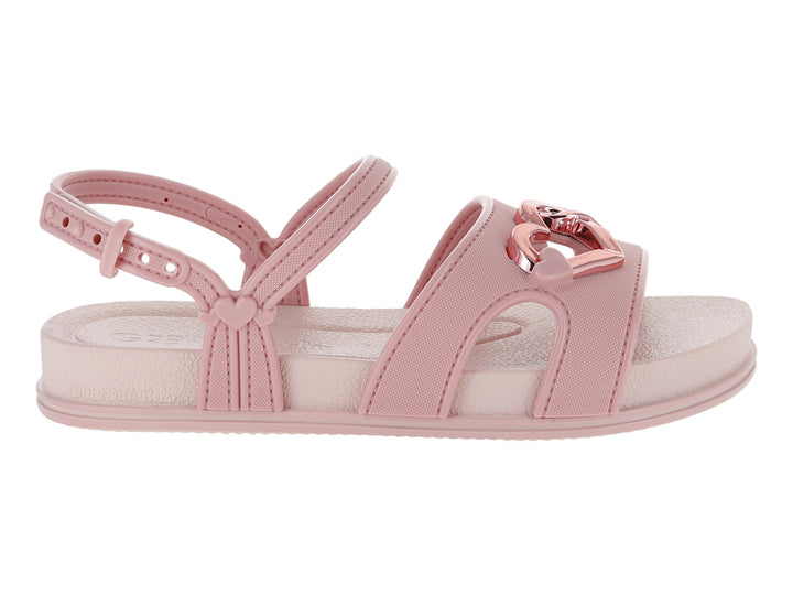 Sandalia plana de color rosa con detalle de corazón metálico y correa ajustable al tobillo.