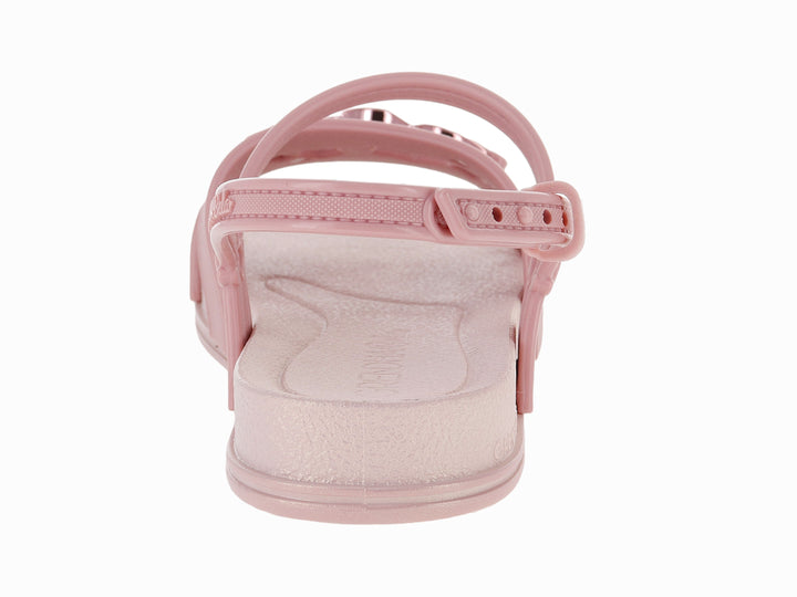 Sandalia plana de color rosa con detalle de corazón metálico y correa ajustable al tobillo.