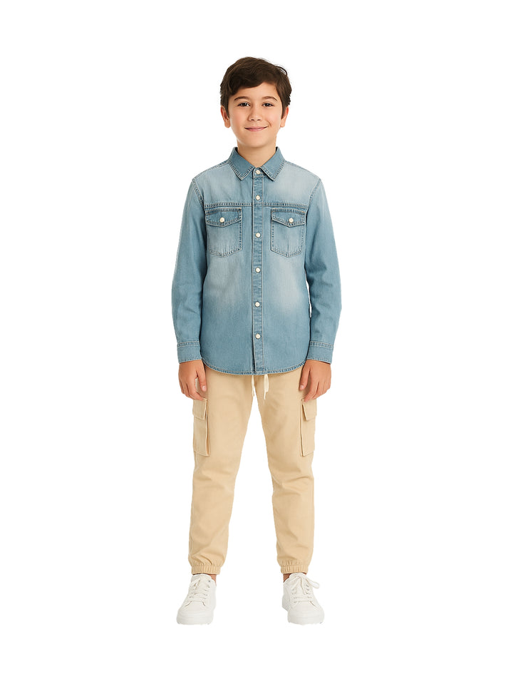 Niño vistiendo un conjunto de camisa de mezclilla azul y pantalones cargo color beige con tenis blancos.