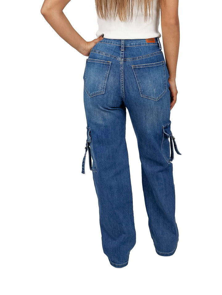 Pantalón cargo de mezclilla azul con bolsillos laterales y detalles de correas, usado por una mujer.