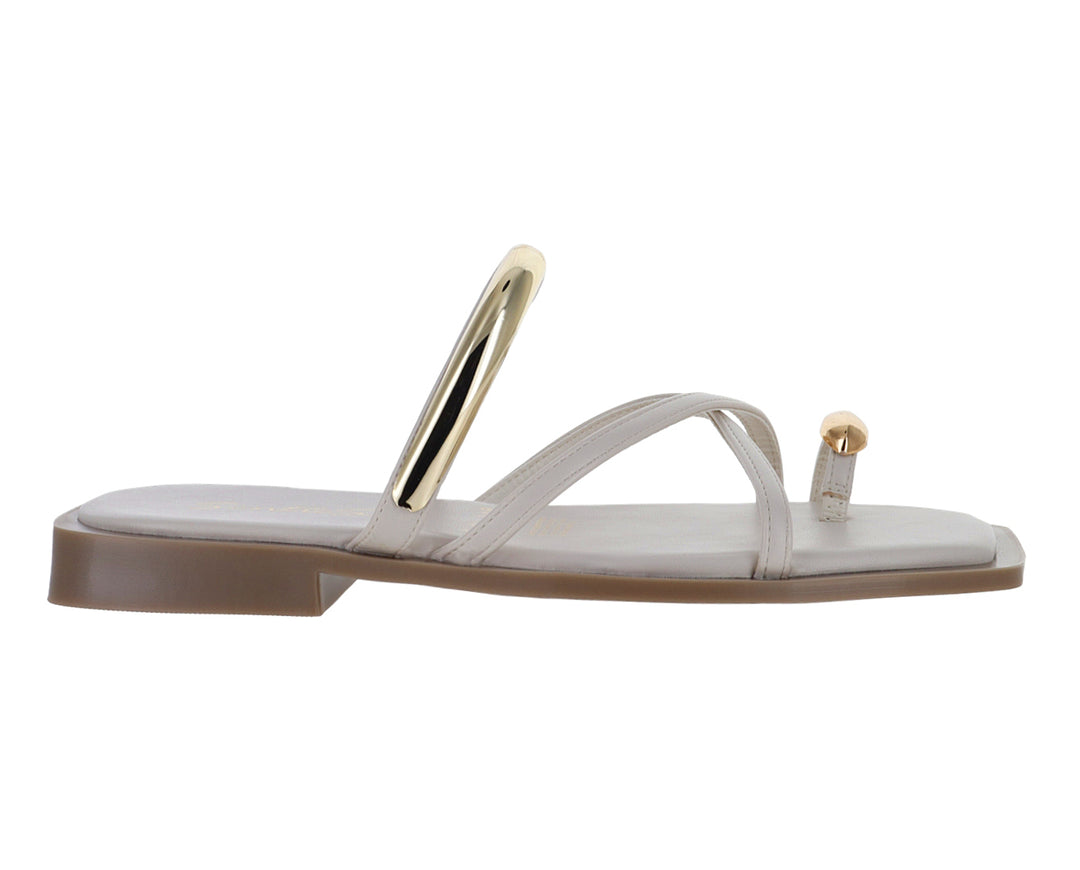 Sandalias planas color latte con detalles metálicos dorados y diseño de tiras cruzadas.