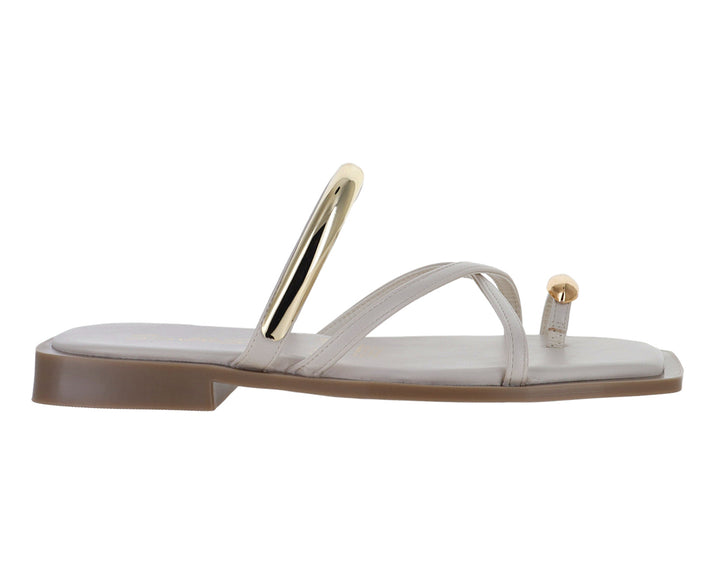 Sandalias planas color latte con detalles metálicos dorados y diseño de tiras cruzadas.