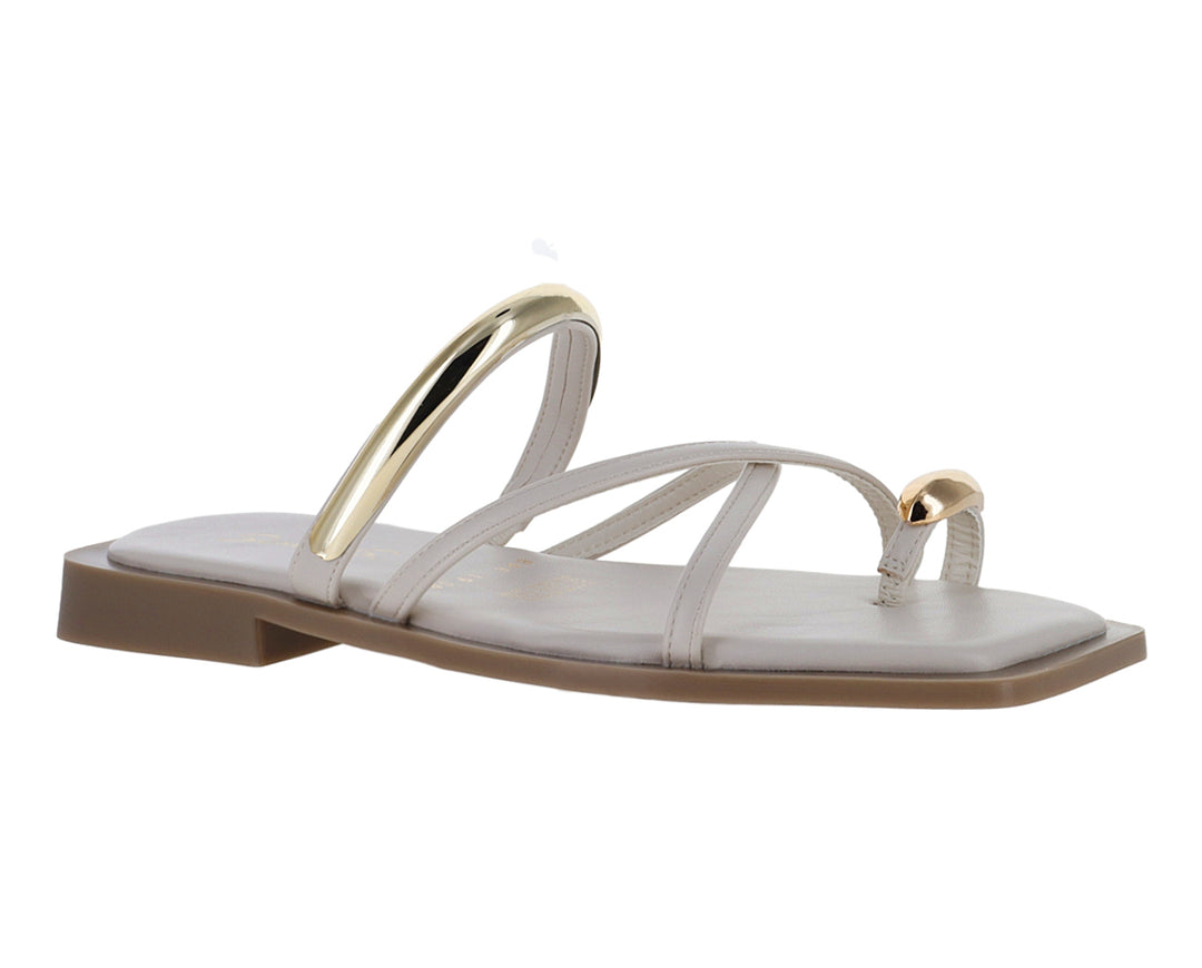 Sandalias planas color latte con detalles metálicos dorados y diseño de tiras cruzadas.