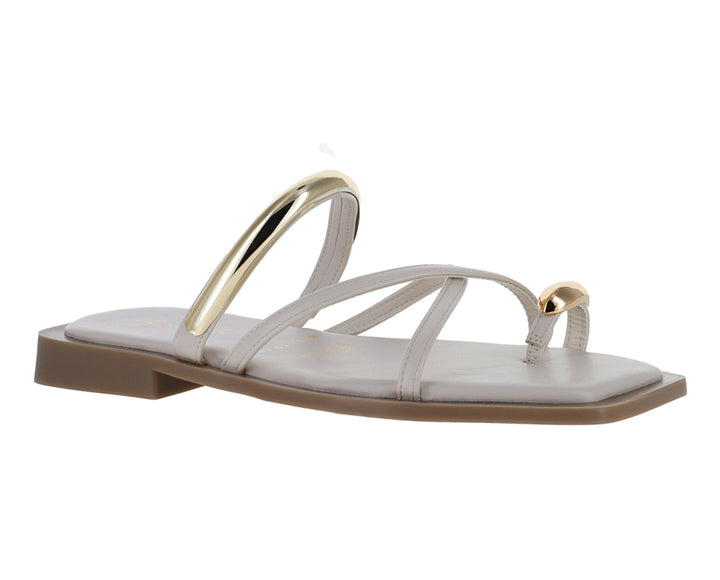 Sandalias planas color latte con detalles metálicos dorados y diseño de tiras cruzadas.