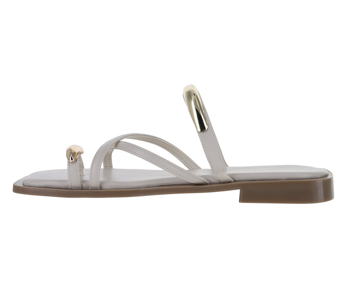 Sandalias planas color latte con detalles metálicos dorados y diseño de tiras cruzadas.