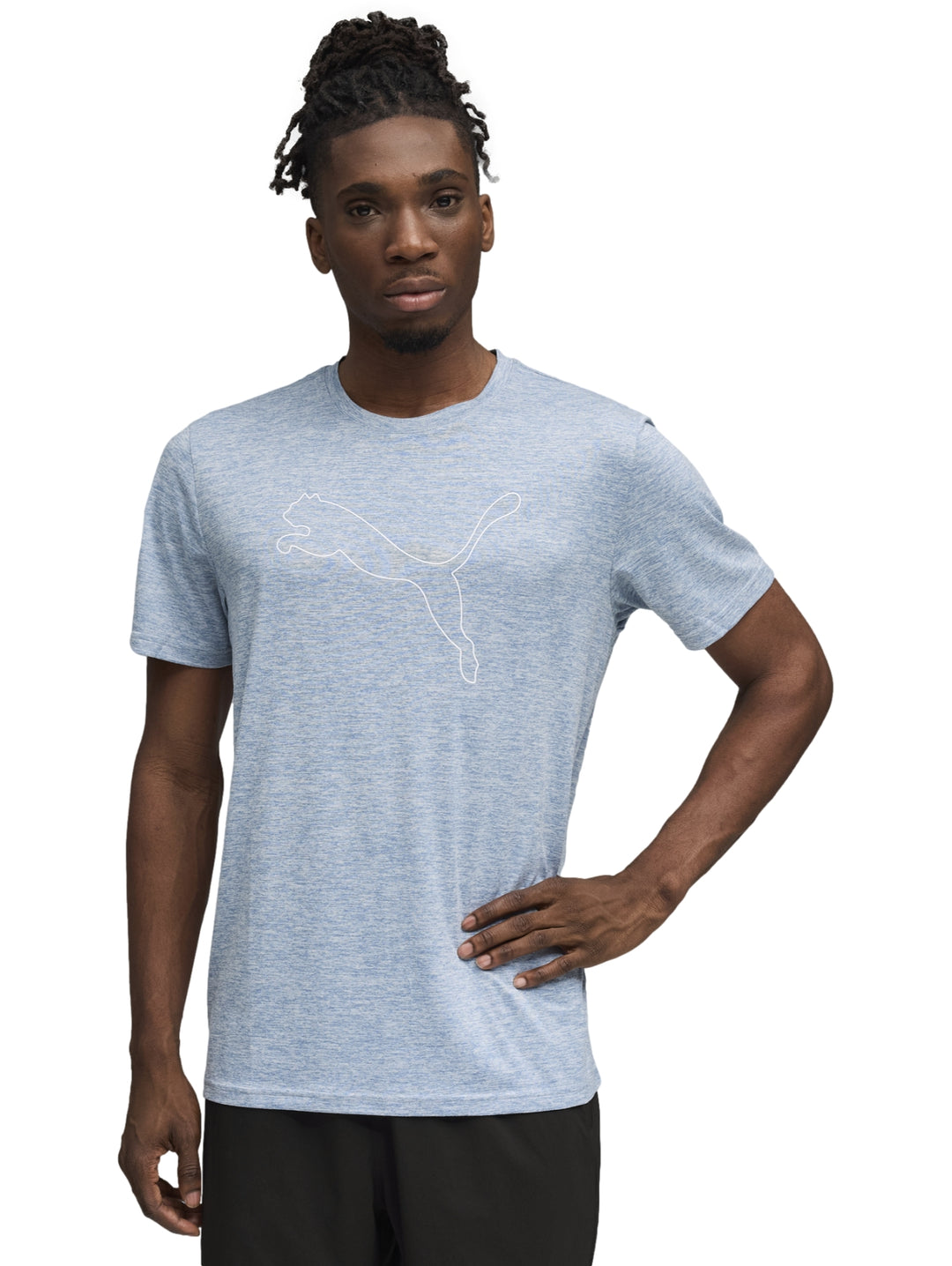 Hombre vistiendo una playera PUMA de color azul claro con el logo del gato en el pecho y pantalones negros.