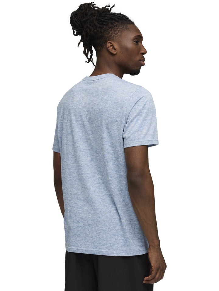 Hombre vistiendo una playera PUMA de color azul claro con el logo del gato en el pecho y pantalones negros.