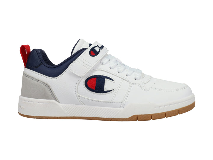 Tenis Champion blancos con detalles en gris y azul marino, correa ajustable y suela color caramelo.