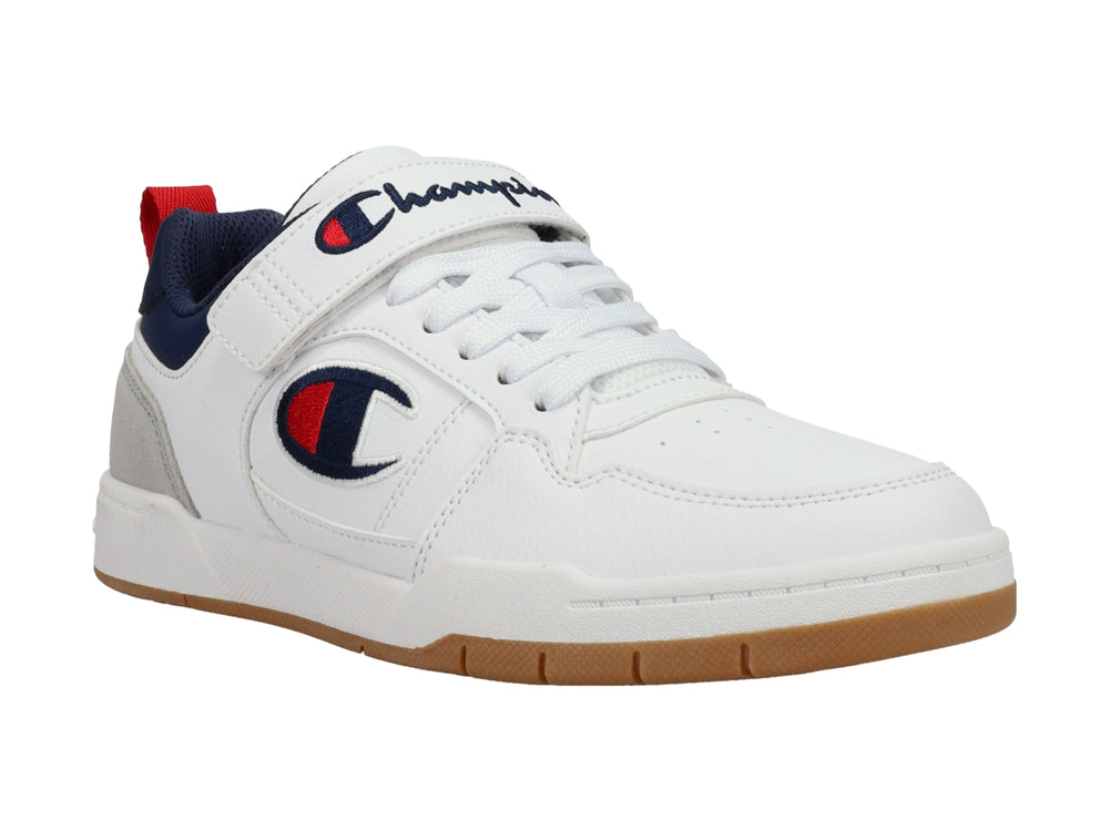 Tenis Champion blancos con detalles en gris y azul marino, correa ajustable y suela color caramelo.