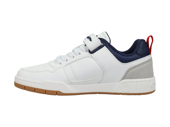 Tenis Champion blancos con detalles en gris y azul marino, correa ajustable y suela color caramelo.