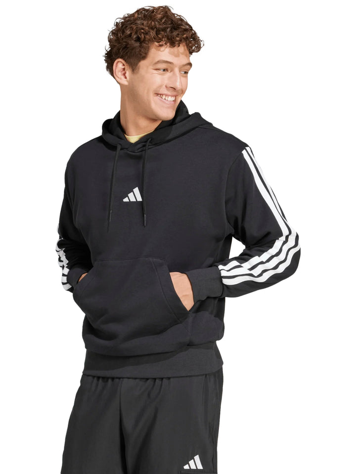 Hombre vistiendo sudadera negra con capucha y rayas blancas en las mangas de la marca Adidas.