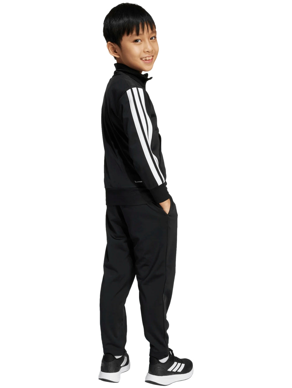 Niño vistiendo un conjunto deportivo Adidas de color negro con franjas blancas en las mangas y pantalones a juego.