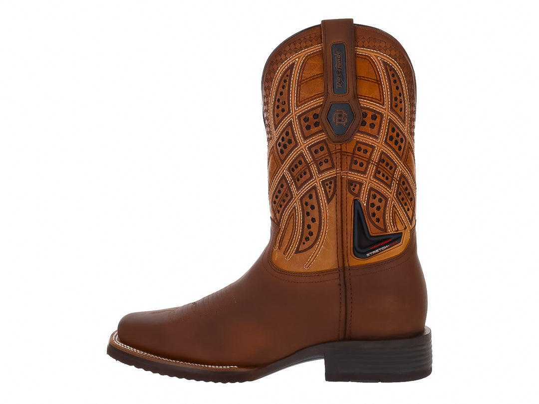 Bota vaquera para hombre de cuero en tonos café y tan con detalles decorativos en la caña.