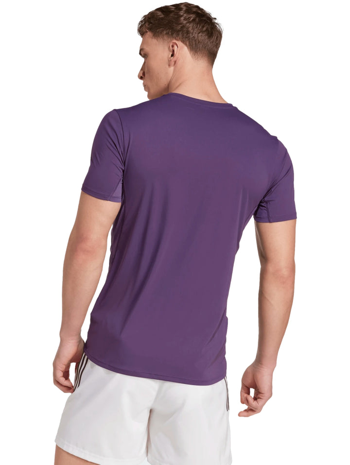 Hombre vistiendo playera de running Adidas color morado y shorts blancos.