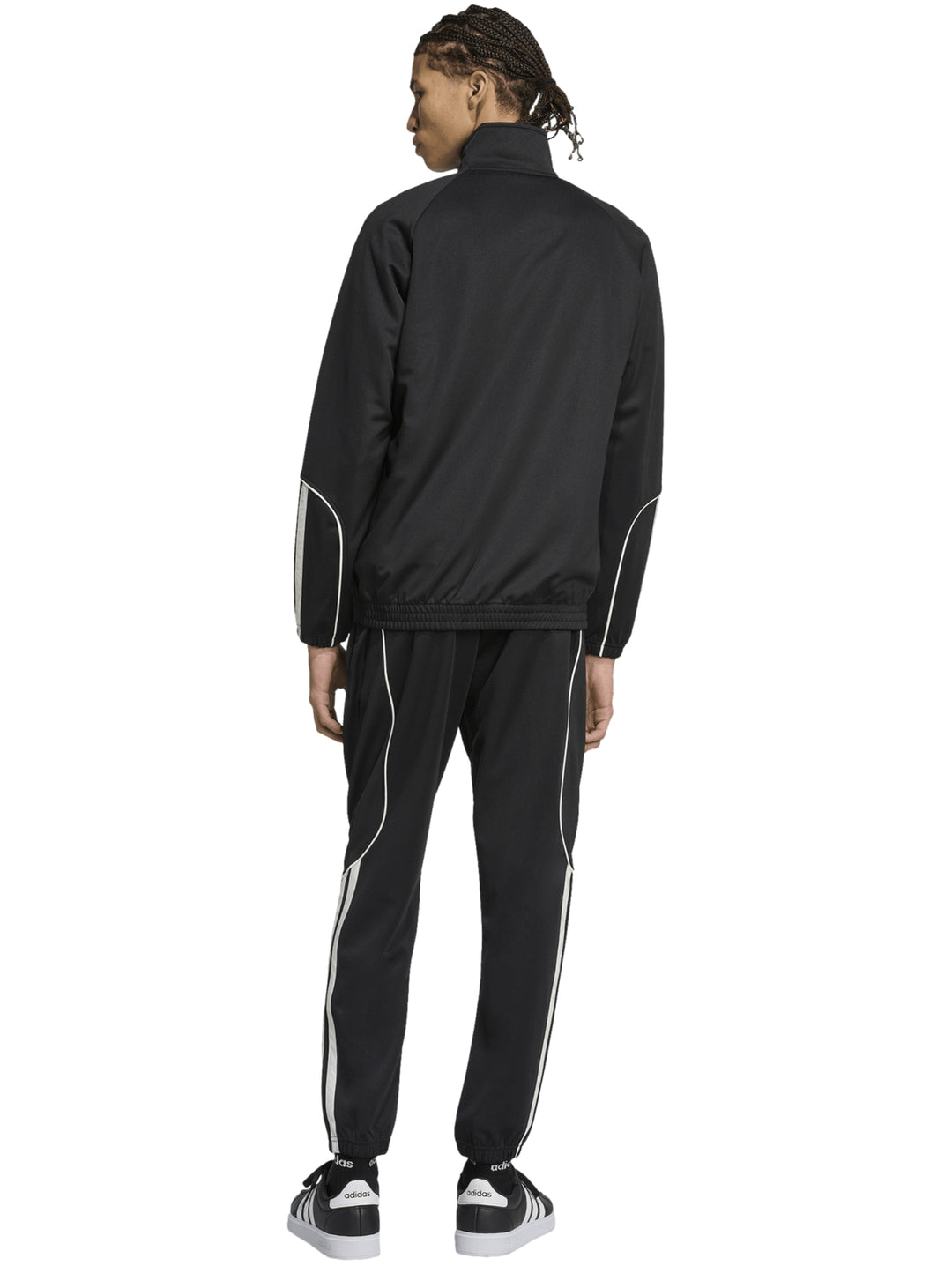 Hombre vistiendo un conjunto deportivo Adidas negro con franjas blancas laterales.