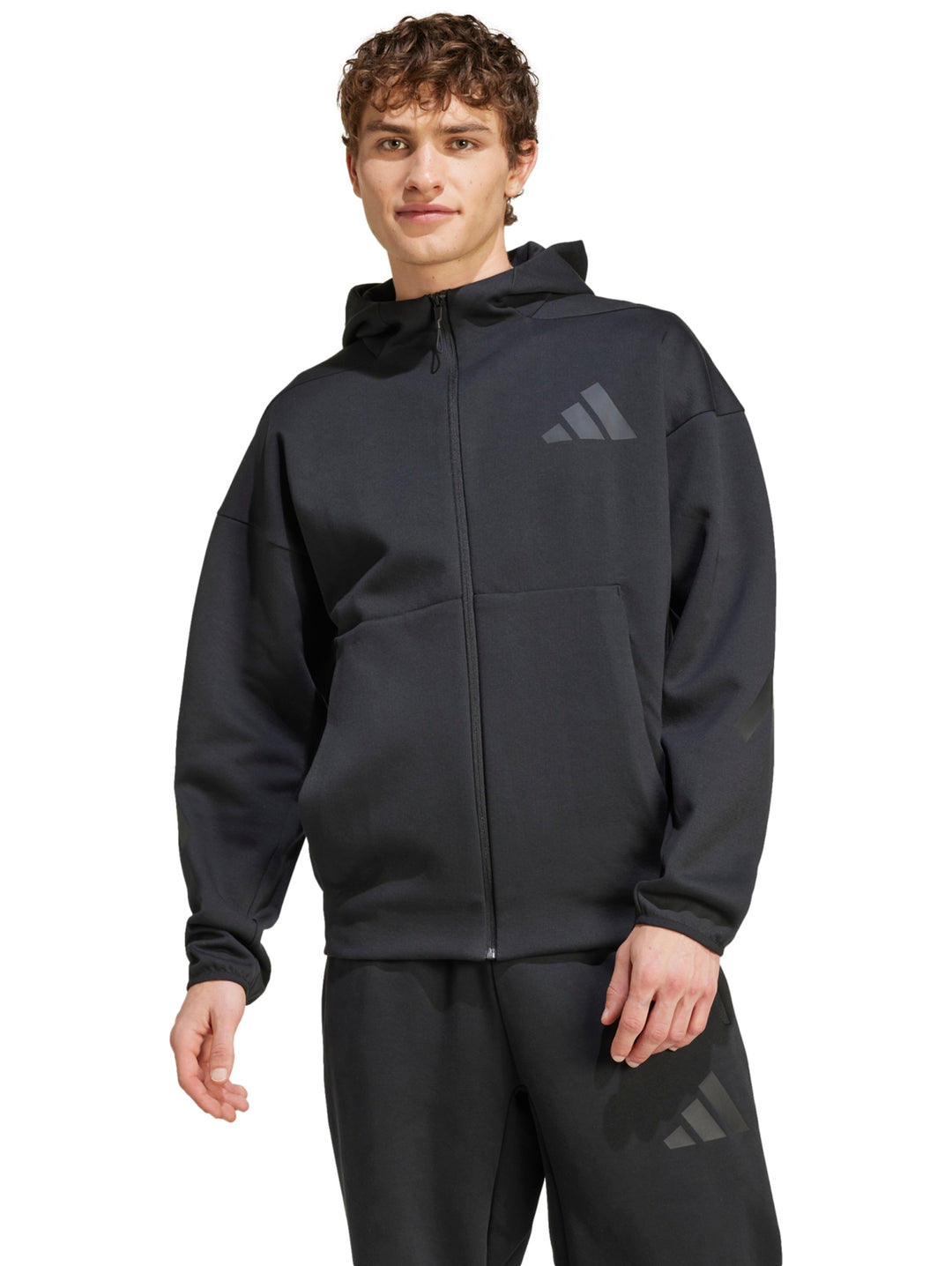 Hombre vistiendo chaqueta deportiva Adidas Z.N.E. de color negro con capucha y cierre frontal.