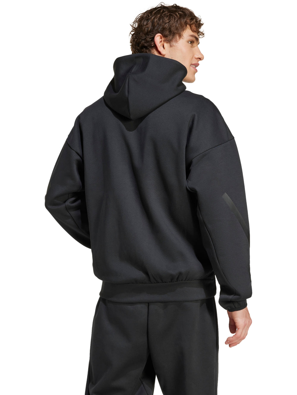 Hombre vistiendo chaqueta deportiva Adidas Z.N.E. de color negro con capucha y cierre frontal.