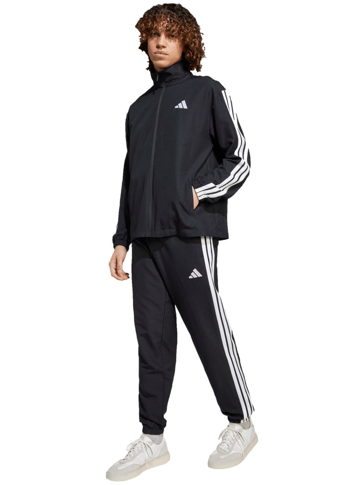 Conjunto deportivo Adidas negro con rayas blancas laterales, compuesto por chamarra y pantalón.