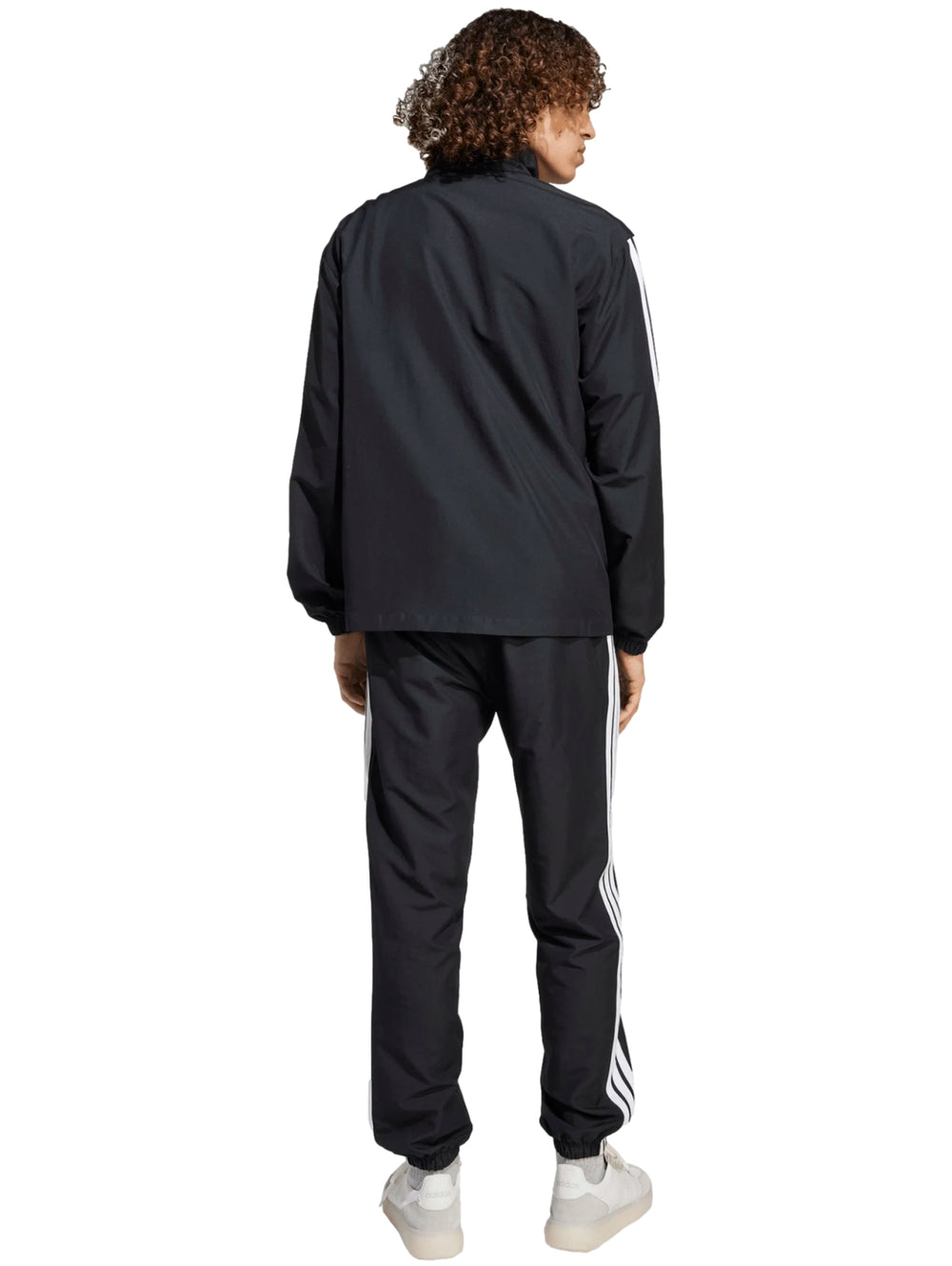 Conjunto deportivo Adidas negro con rayas blancas laterales, compuesto por chamarra y pantalón.