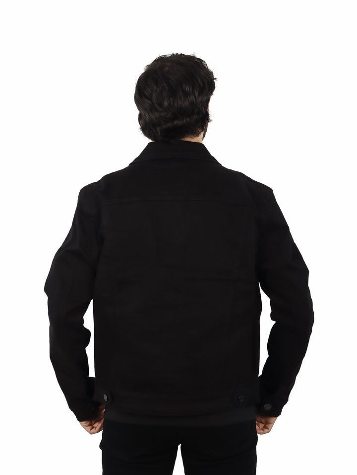 Hombre vistiendo una chamarra de mezclilla color negro sobre una playera negra.