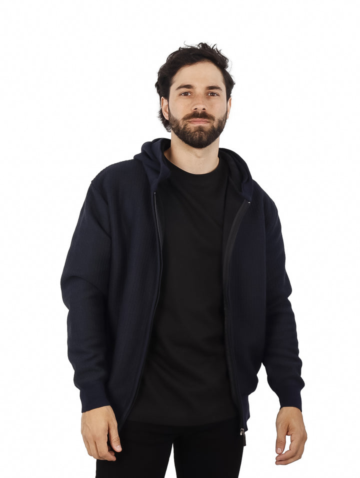 Hombre vistiendo una sudadera con capucha y cierre de color azul marino.