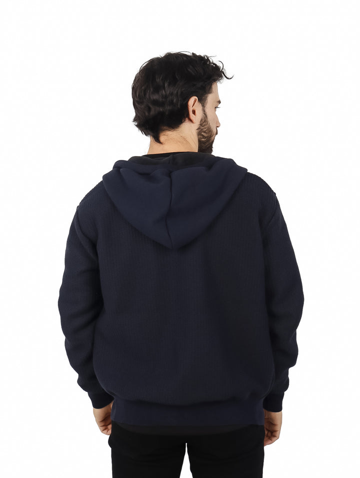 Hombre vistiendo una sudadera con capucha y cierre de color azul marino.