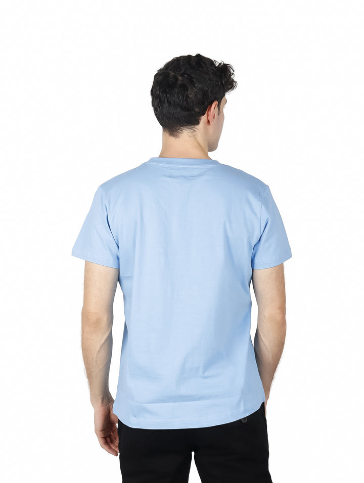 Hombre vistiendo playera azul de manga corta con estampado gráfico frontal de un ángel y dinero.