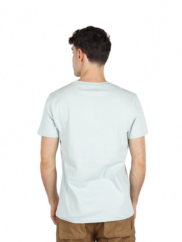 Hombre vistiendo playera color verde claro con estampado gráfico de un oso y texto en el pecho.