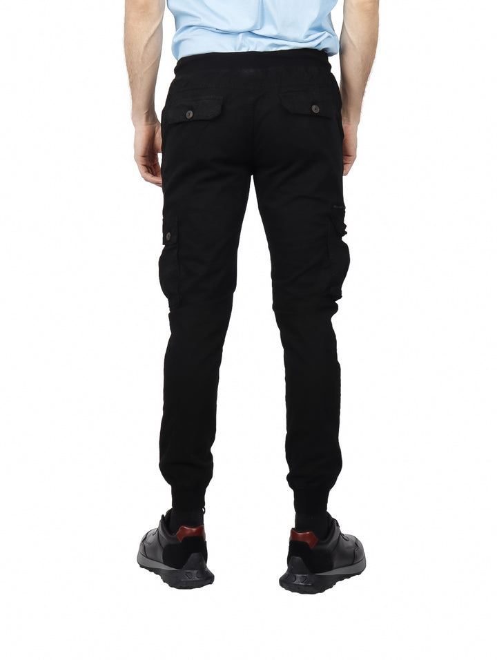 Hombre vistiendo pantalones jogger cargo color negro con bolsillos laterales y puños elásticos.